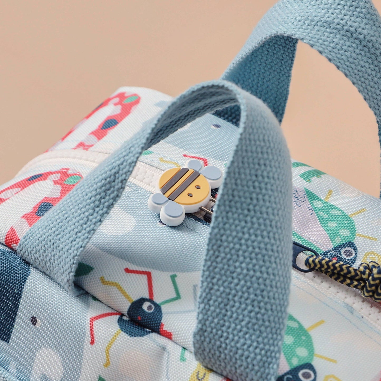 Children's bag with colorful car pattern and blue handle on a beige background
