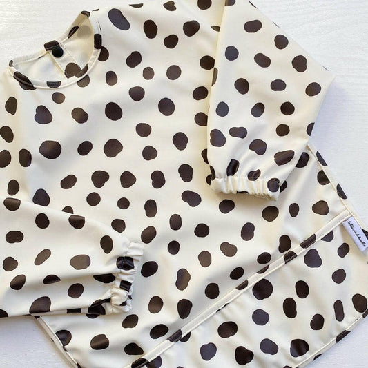 Black and white polka dot long sleeve bib on a white background