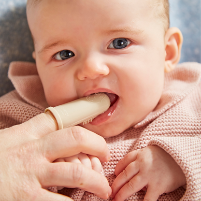 Baby holding a wooden toothbrush with a blurred background