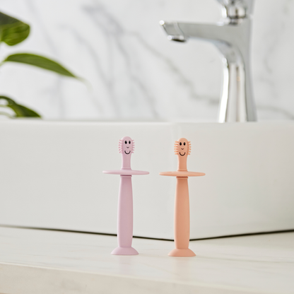 Two children's toothbrushes with smiling faces on a bathroom counter.