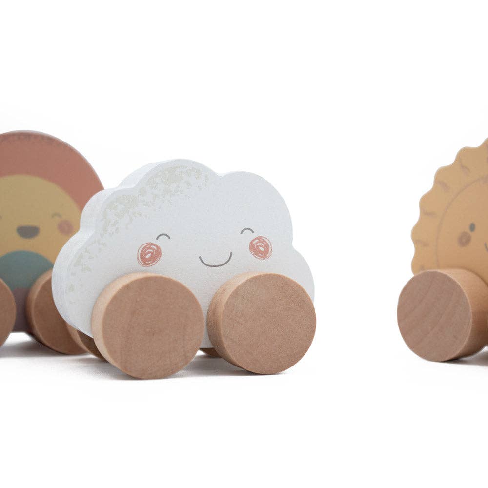 Wooden toys shaped like a cloud, a sun and a rainbow on a white background