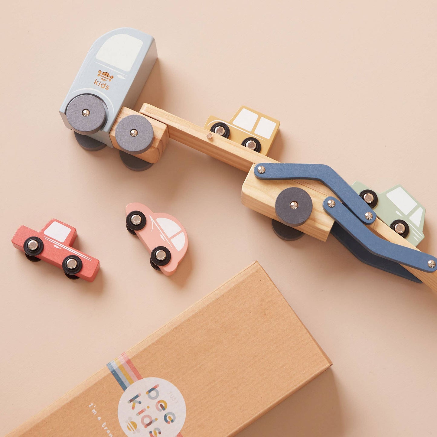 Wooden toy bulldozer with attached cars on a beige background