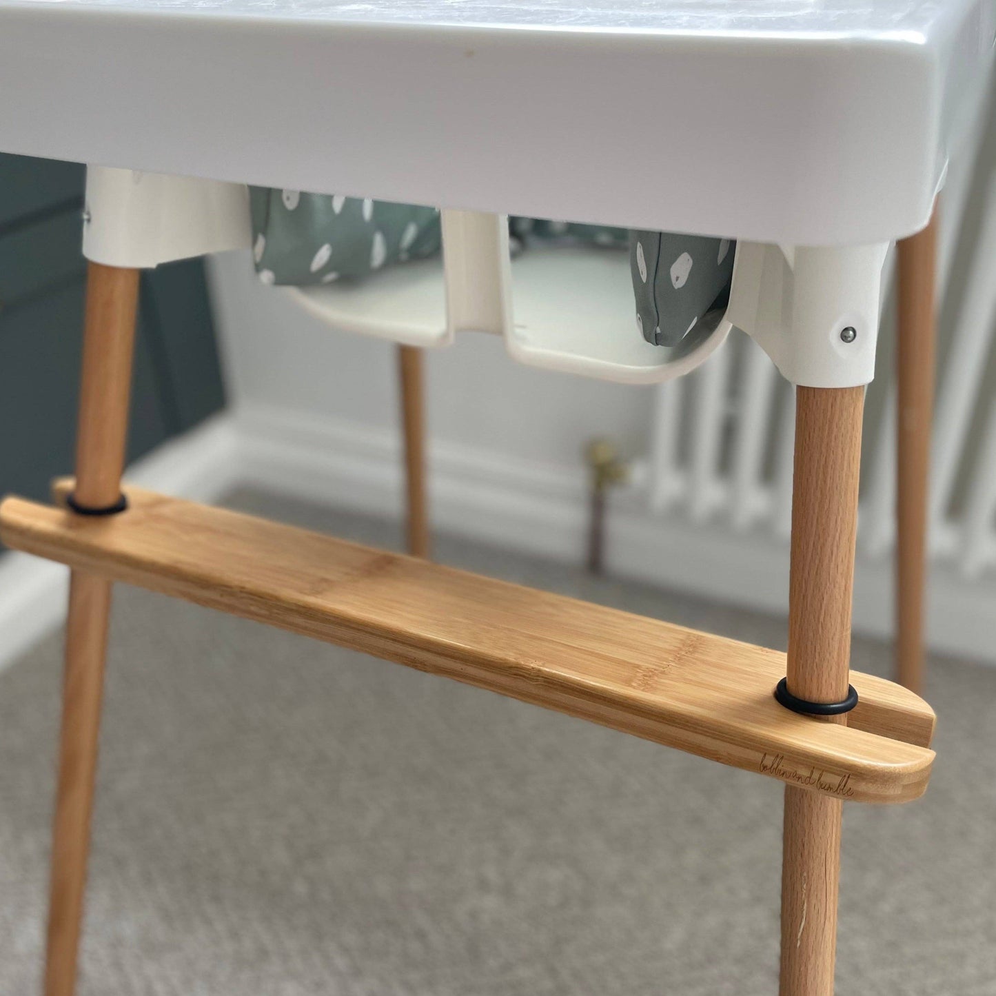 Wooden footrest for IKEA highchair with white top in a neutral setting