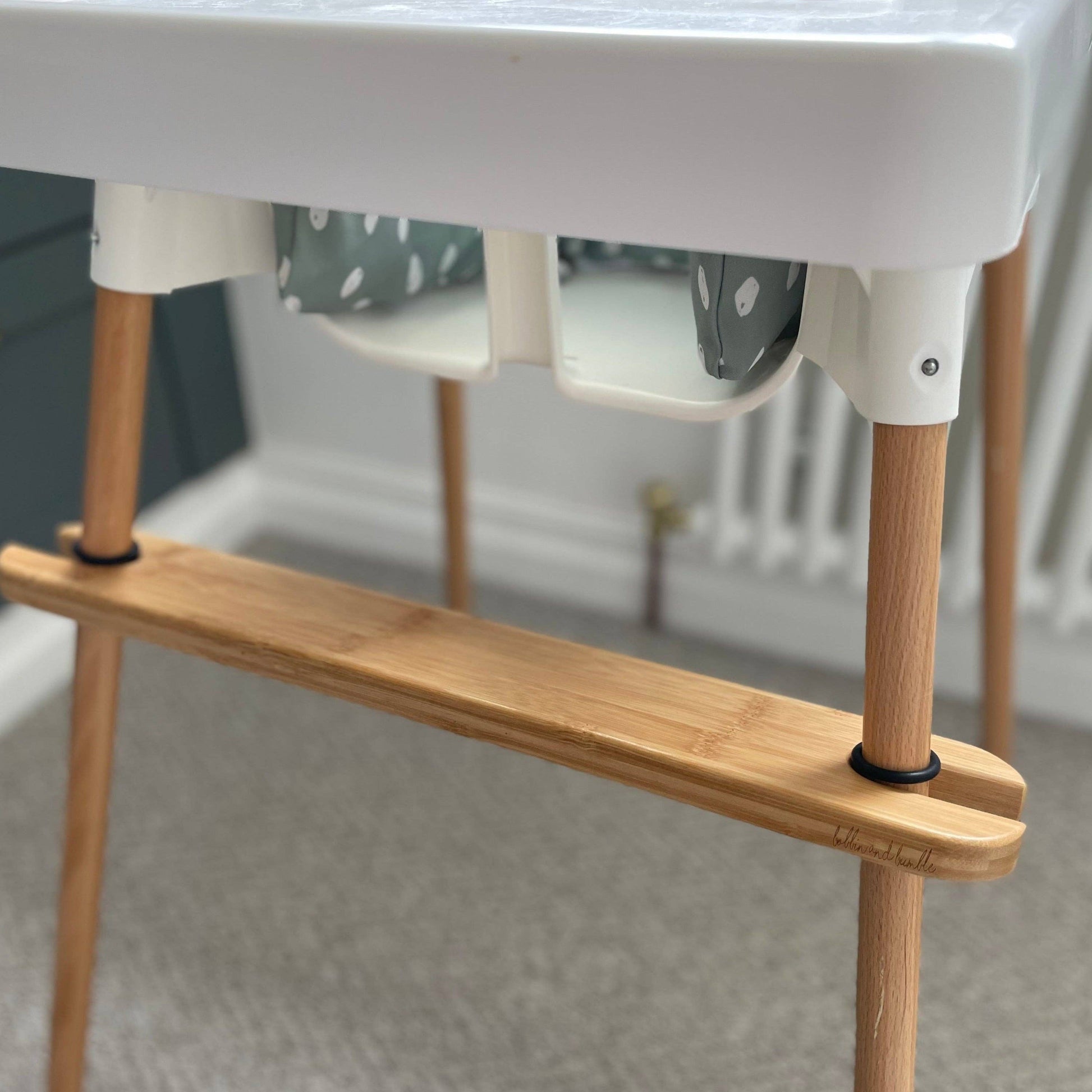 Wooden footrest for IKEA highchair with white top in a neutral setting