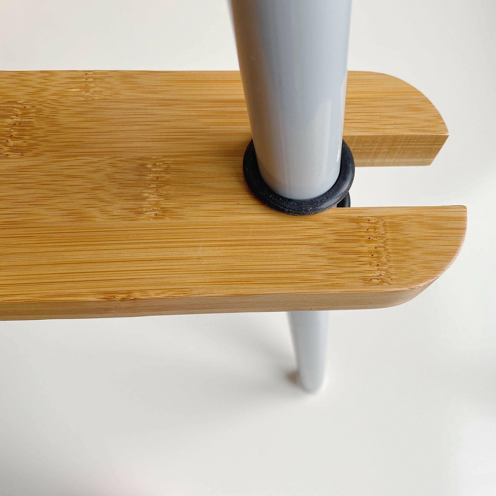 Close-up of a wooden footrest on highchair with a black cylindrical stopper on a white background