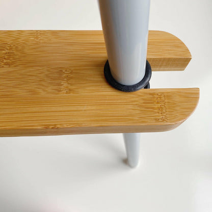 Close-up of a wooden footrest on highchair with a black cylindrical stopper on a white background
