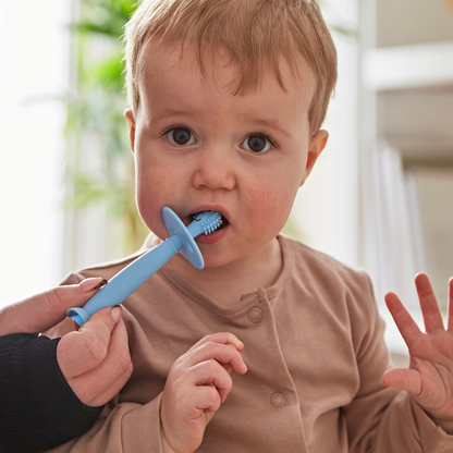 Child with a blue toothbrush in a home setting