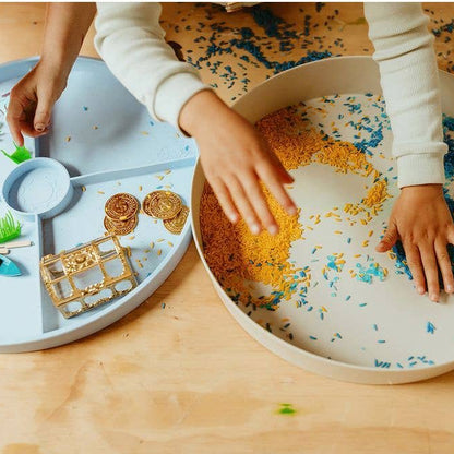 Children playing with a sand tray on a wooden surface