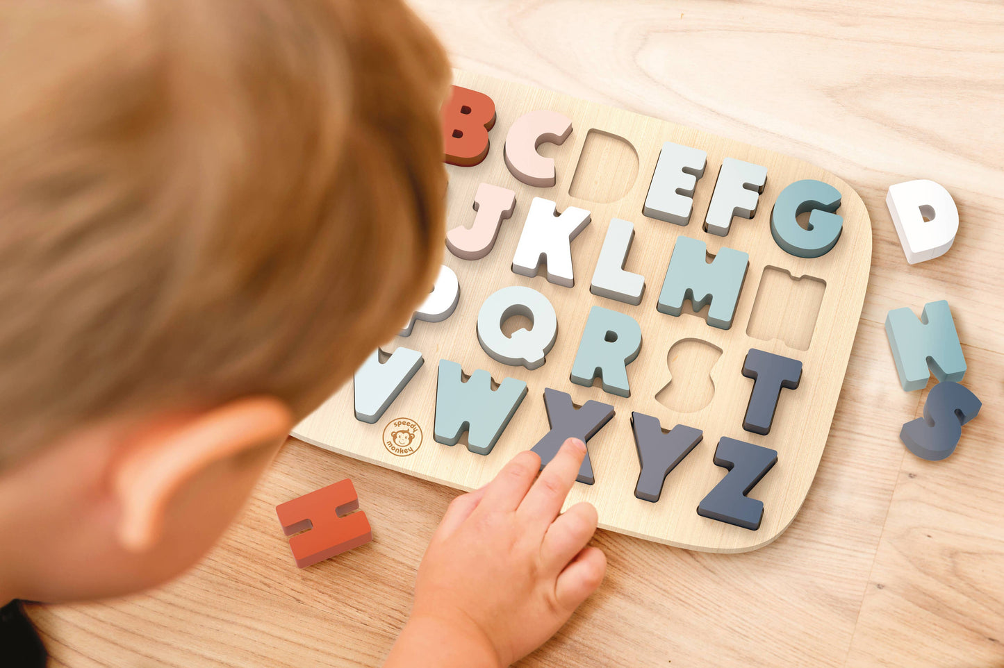Child playing with a wooden alphabet puzzle on a wooden surface