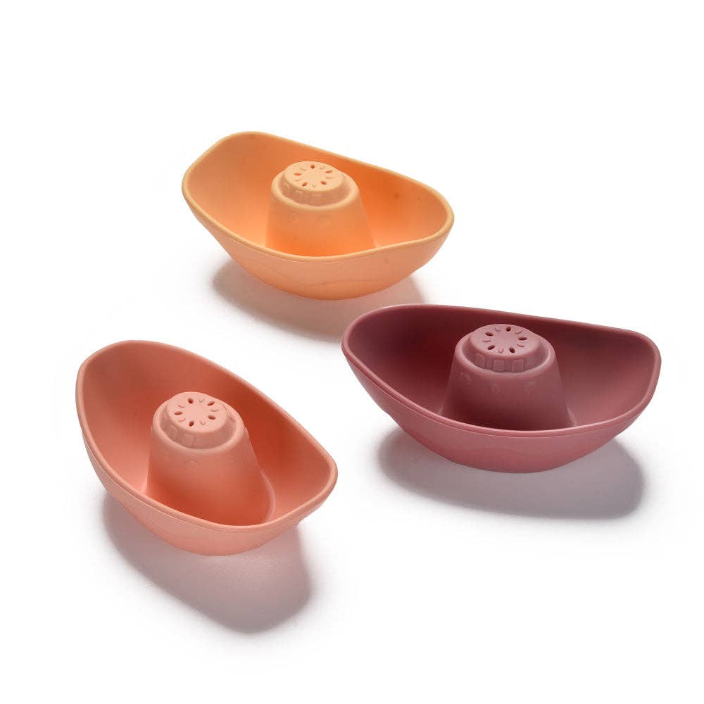 Three colorful ceramic boats with small cylindrical containers on a white background