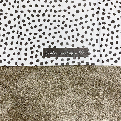 Patterned splashmat with black dots on a white background and a visible brand label.