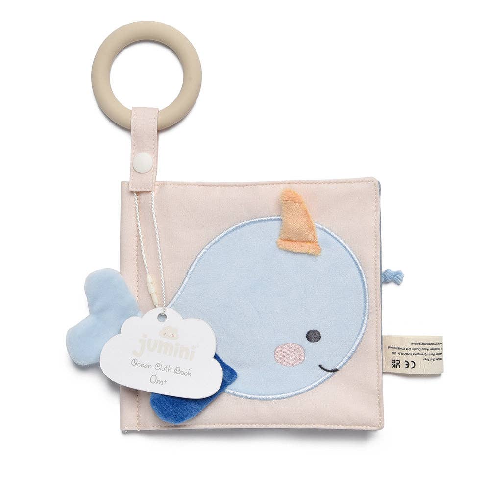 Baby book with whale design and rattle on a white background