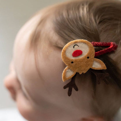 Child's hair with a reindeer-shaped hair clip on a neutral background