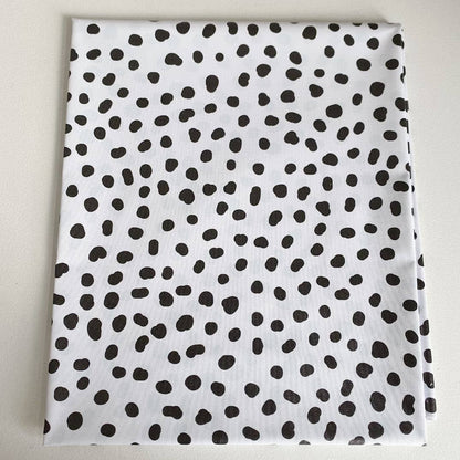 White splashmat with black polka dot pattern on a light grey background