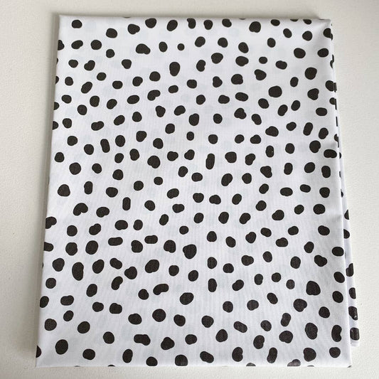 White splashmat with black polka dot pattern on a light grey background