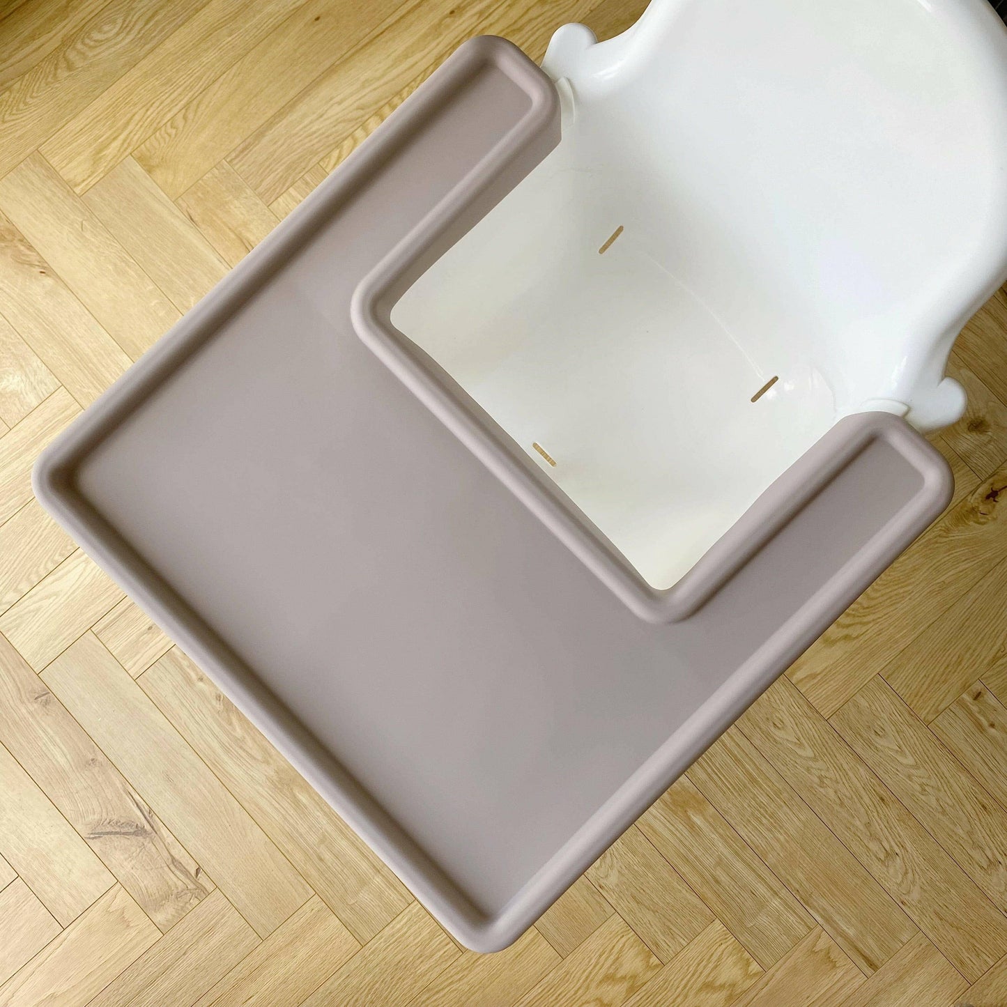 Taupe silicone highchair cover for tray on a white IKEA highchair on a wooden floor