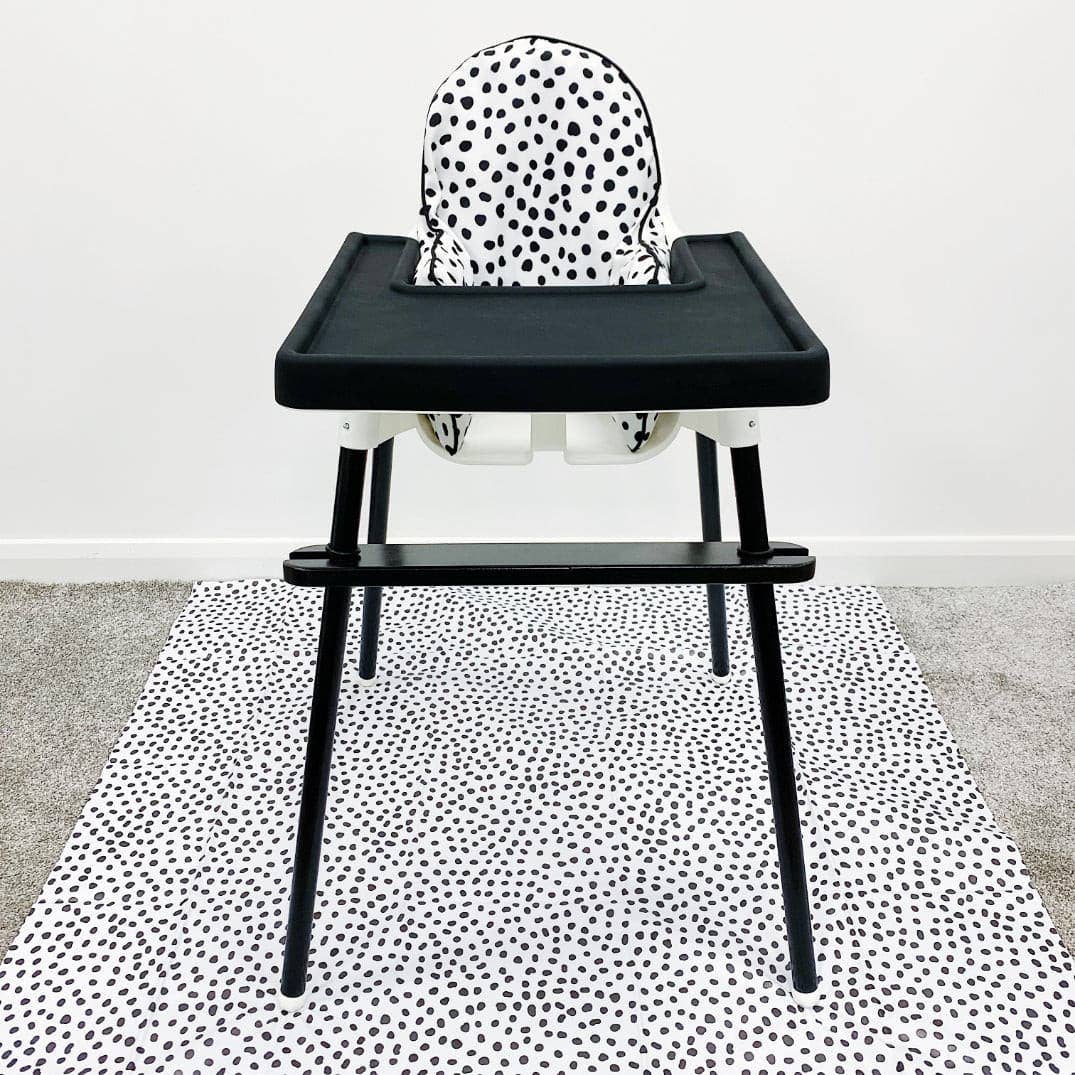 Black high chair with a white cushion with black dots on a white background