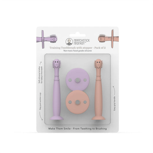 Packaging of Matchstick Monkey training toothbrushes with stoppers in purple and pink on a white background.