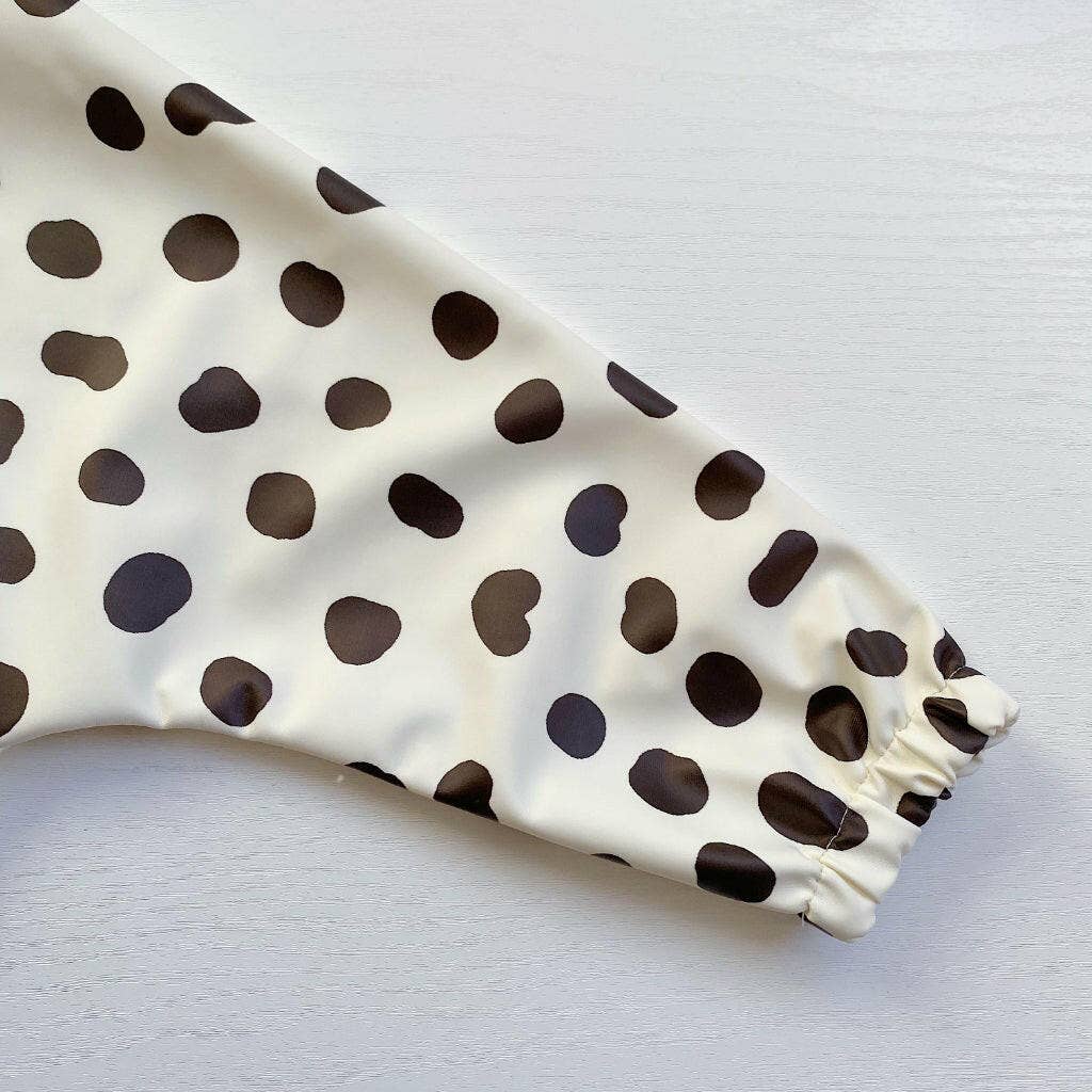 White bib sleeve with black polka dots on a light grey background