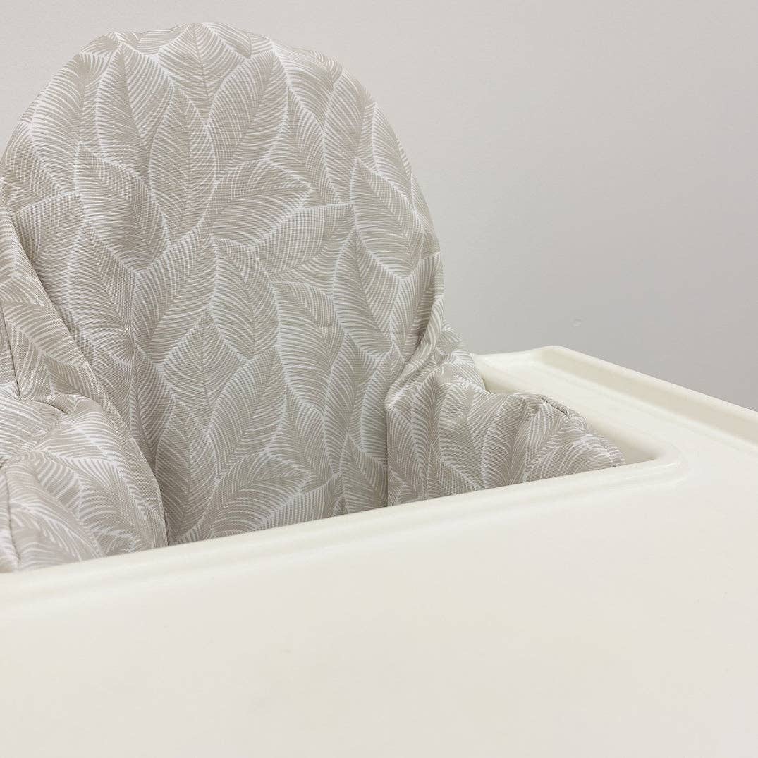 Close-up of a highchair cushion cover with a leaf pattern against a plain background
