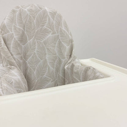 Close-up of a highchair cushion cover with a leaf pattern against a plain background