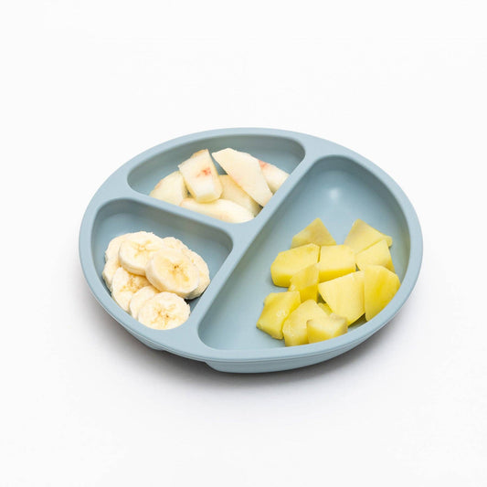 Light blue divided plate with banana and apple pieces on a white background
