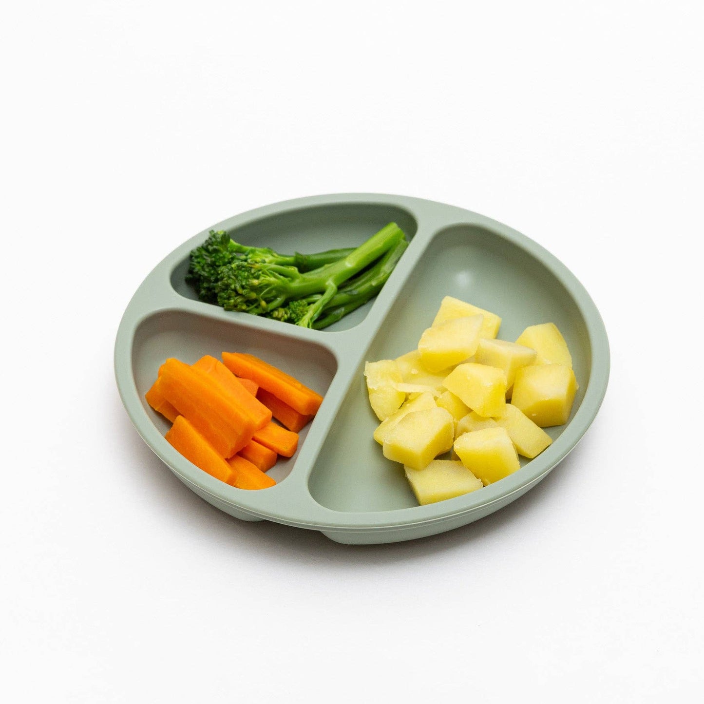Divided green plate with carrots, broccoli, and pineapple on a white background