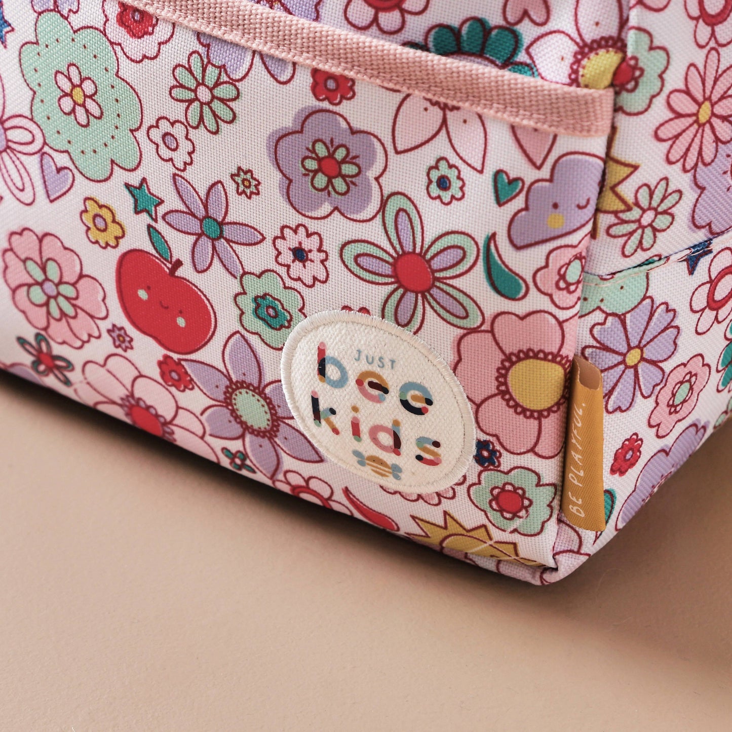Floral-patterned pouch with 'Just Bee Kids' label on a beige background