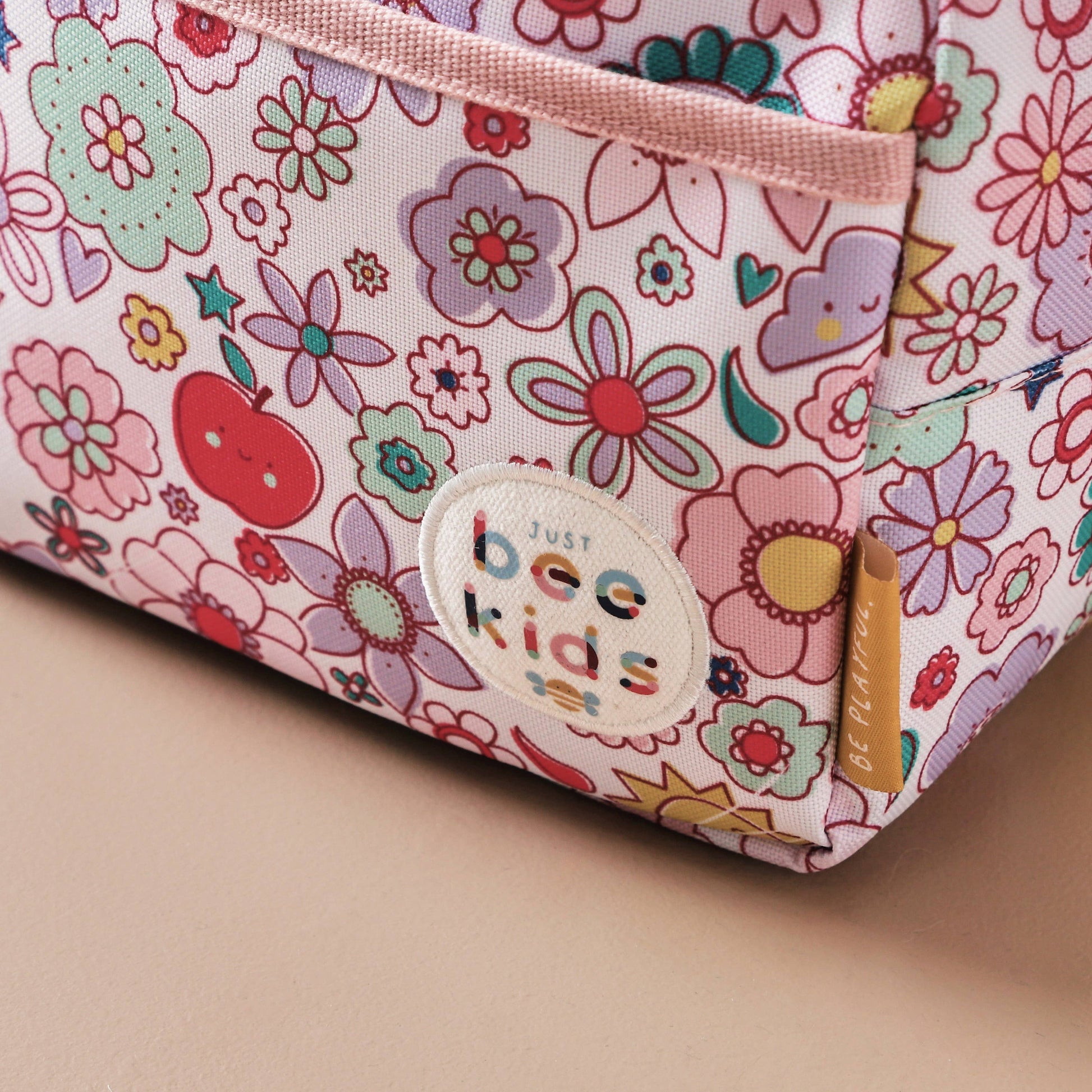 Floral-patterned pouch with 'Just Bee Kids' label on a beige background