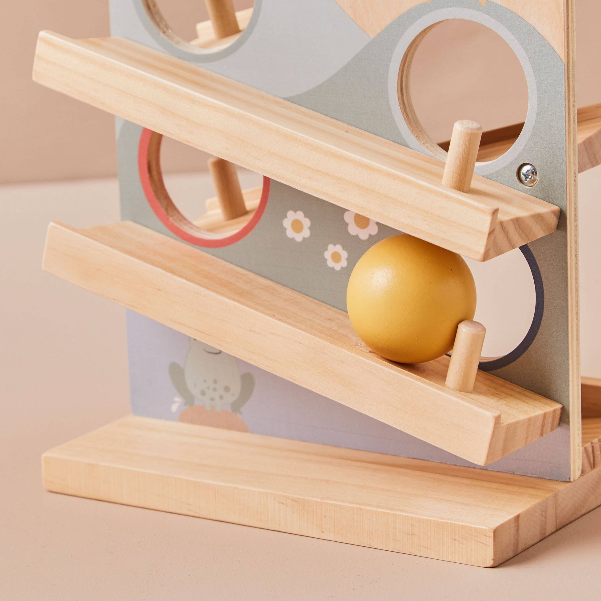 Wooden toy with a yellow ball on a ramp against a neutral background