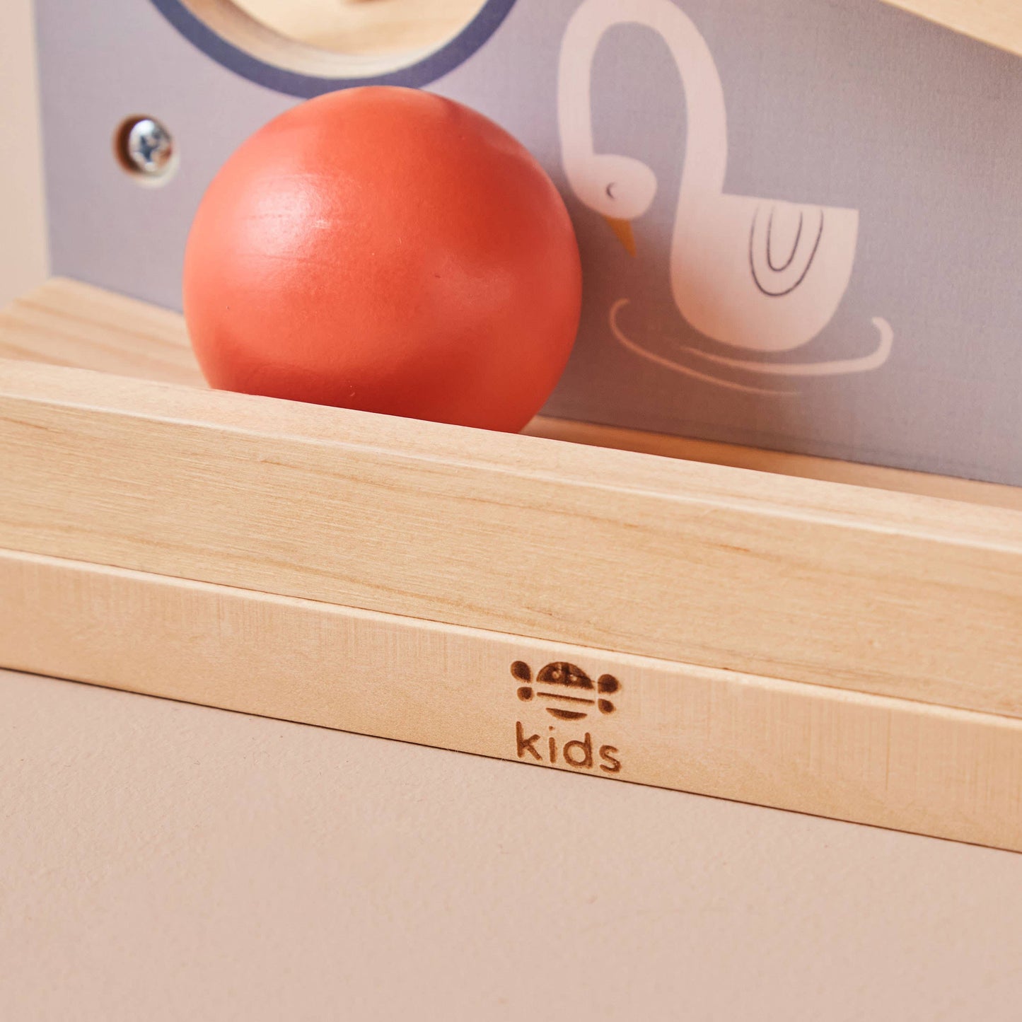 Red ball on a wooden surface with 'kids' branding in the background