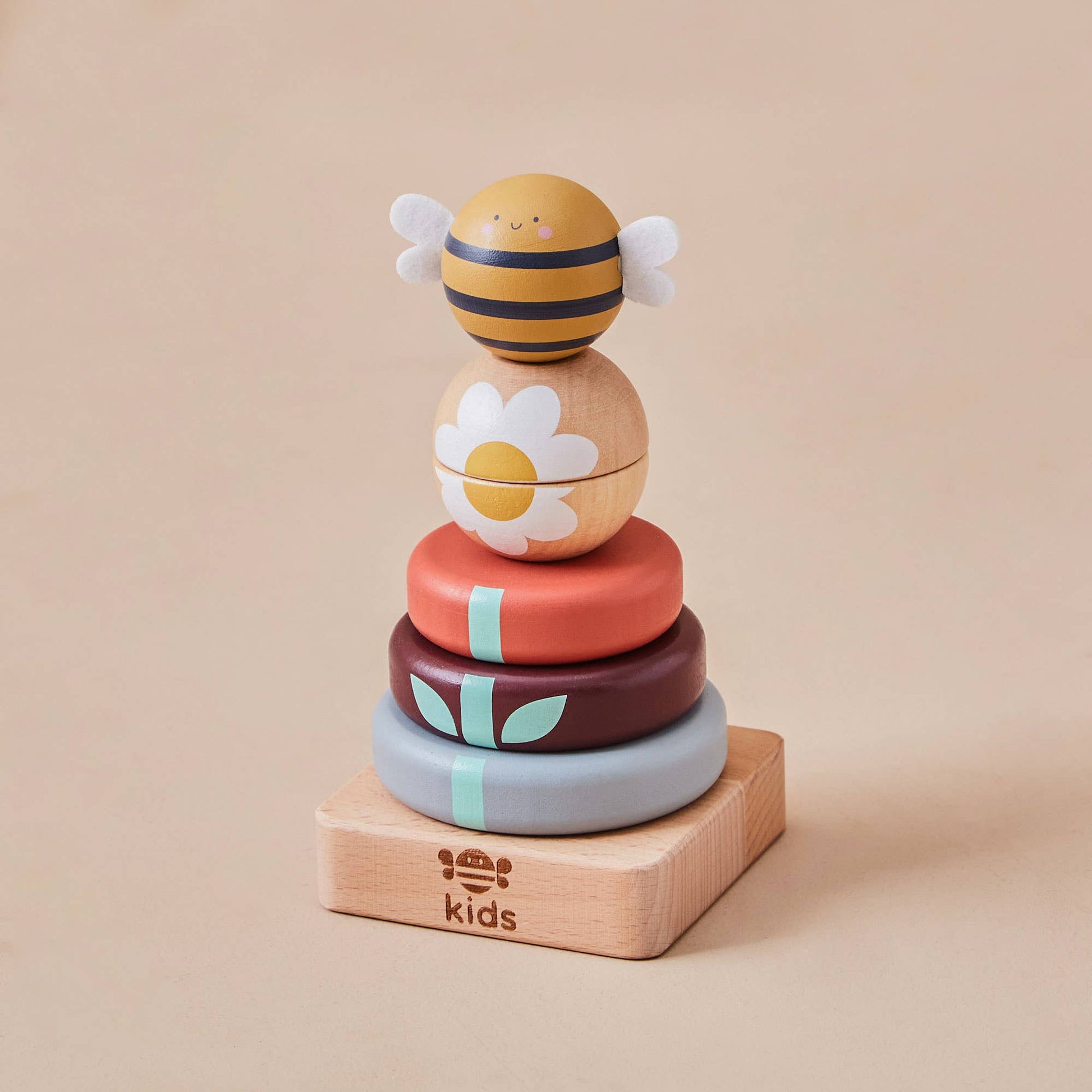 Stack of colorful wooden toys with a bee design on a beige background