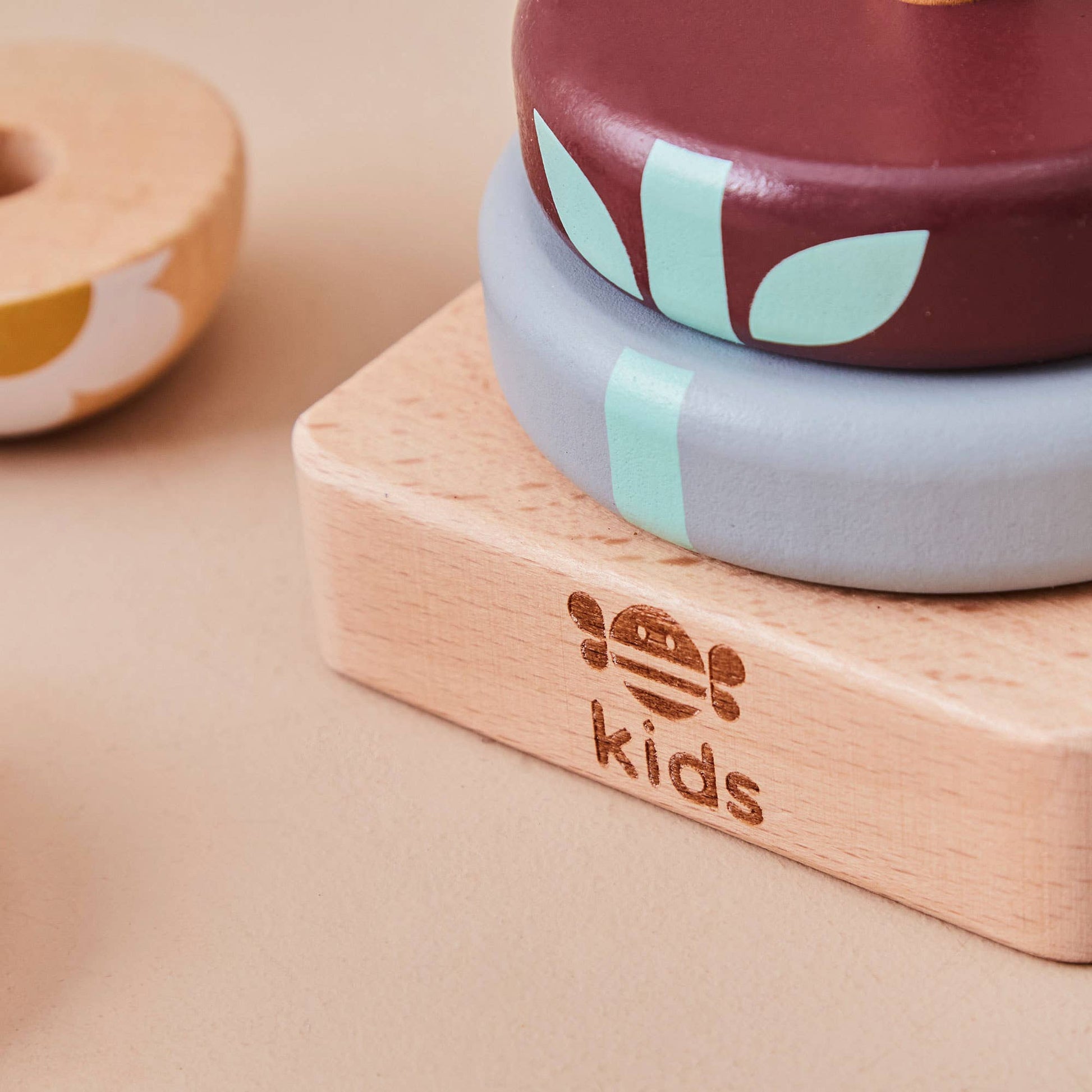 Stack of wooden rings with a 'kids' logo on a beige background