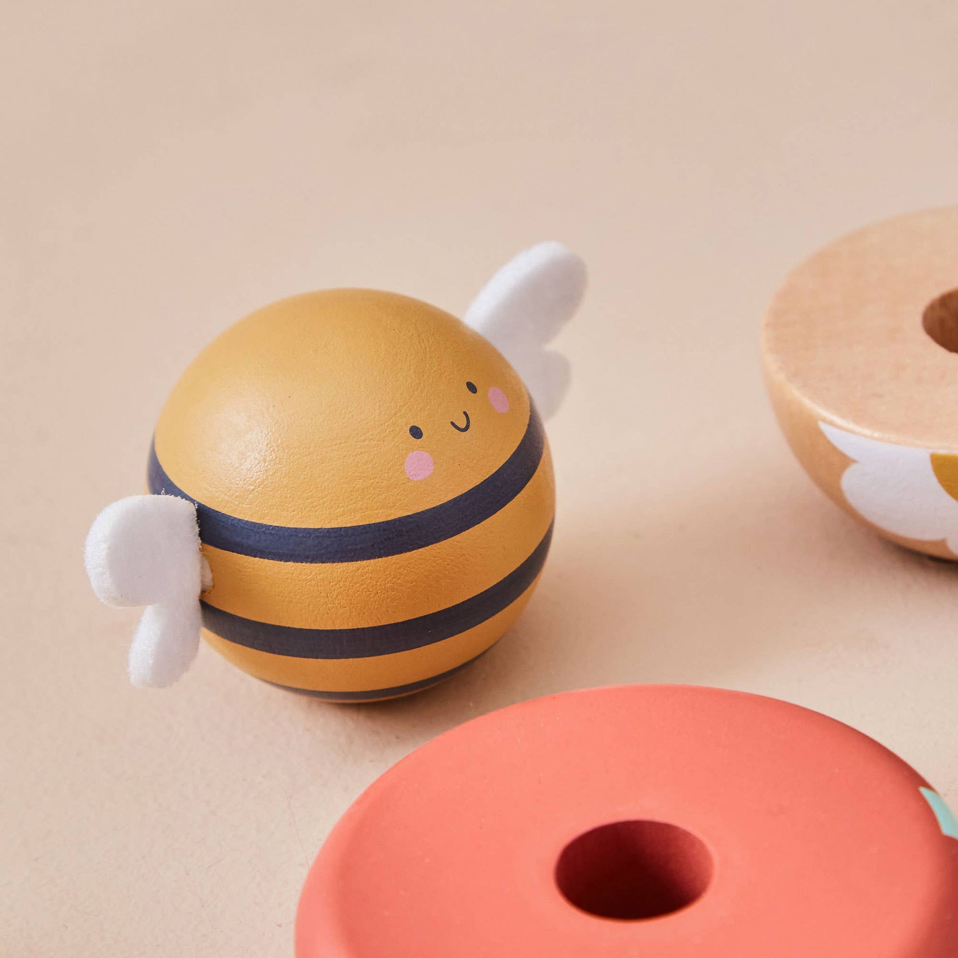 Toy bee with striped body and white wings on a beige background