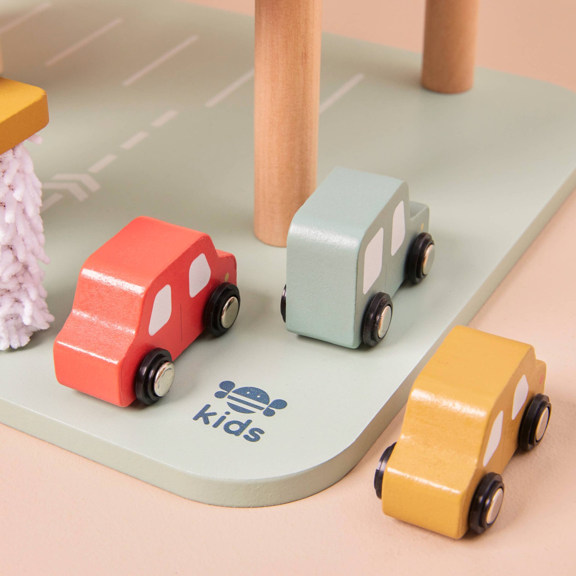 Wooden toy cars on a road with 'kids' brand logo.