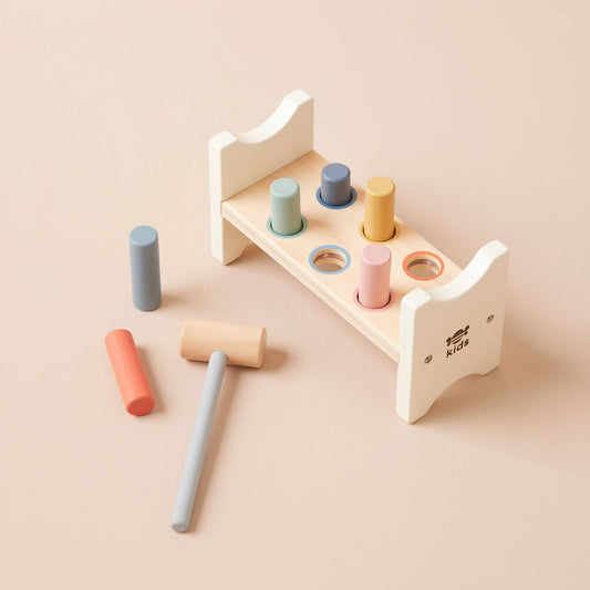 Wooden hammer and block set with pastel-colored blocks on a beige background