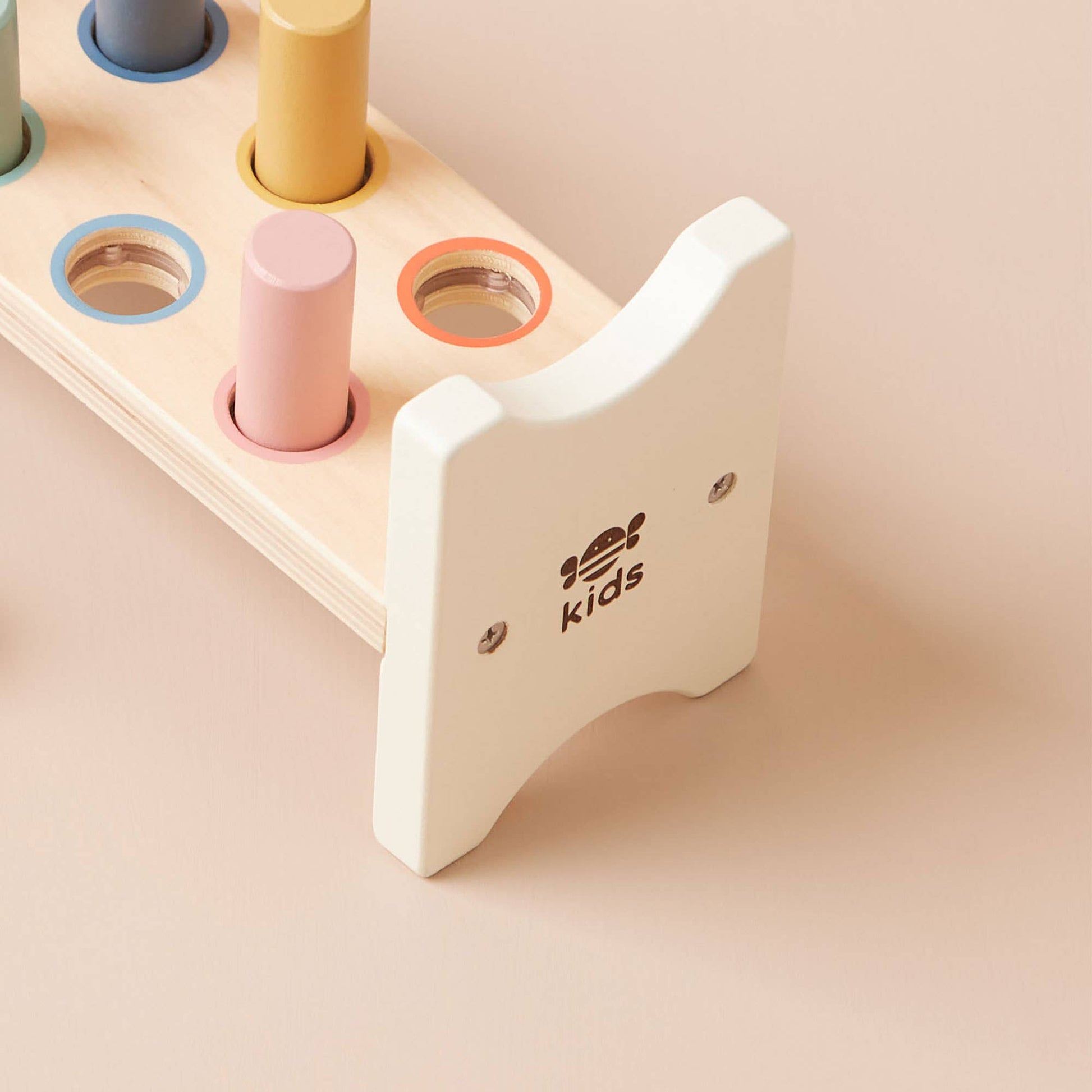 Wooden toy with colourful cylindrical shapes on a beige background, featuring the brand 'kids'.