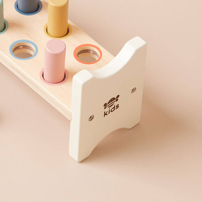 Wooden toy with colourful cylindrical shapes on a beige background, featuring the brand 'kids'.