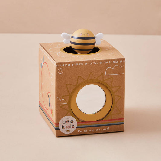 Toy bee inside a cardboard box with 'bee kids' branding on a beige background