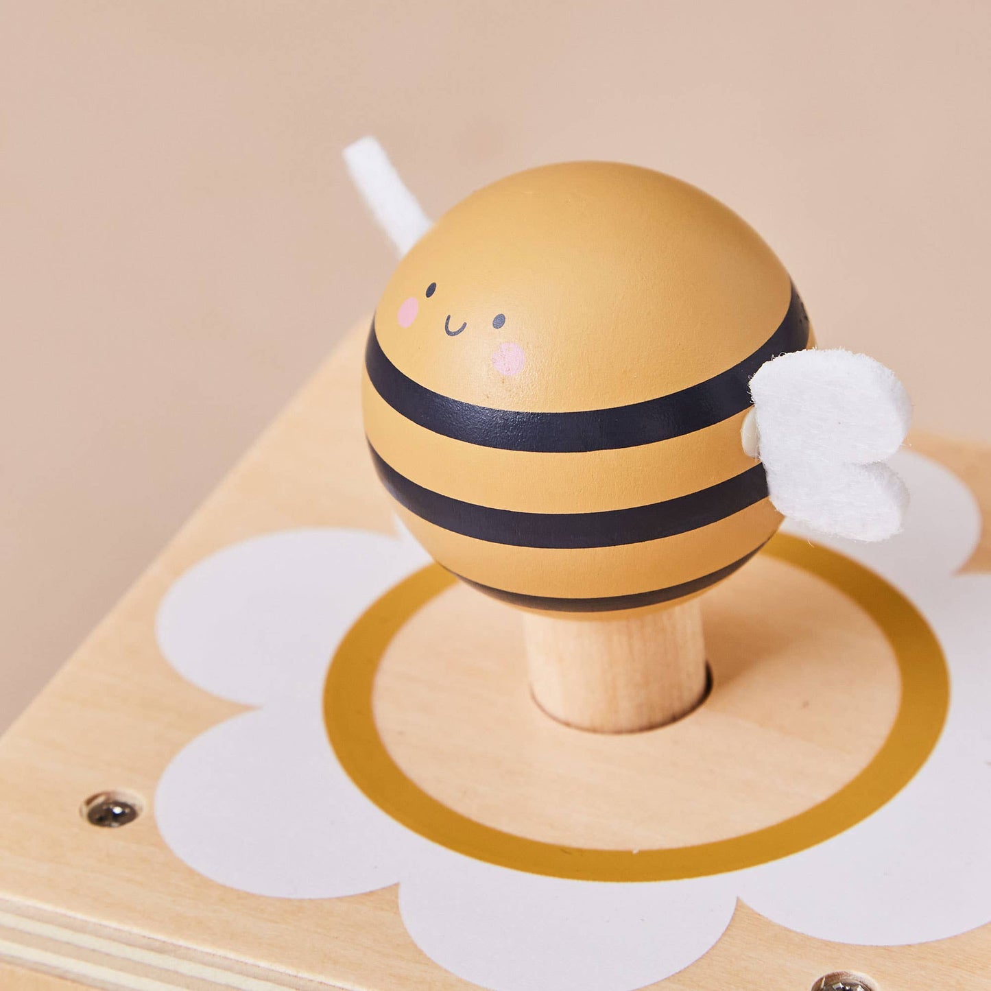 Wooden toy bee on a wooden base with a beige background