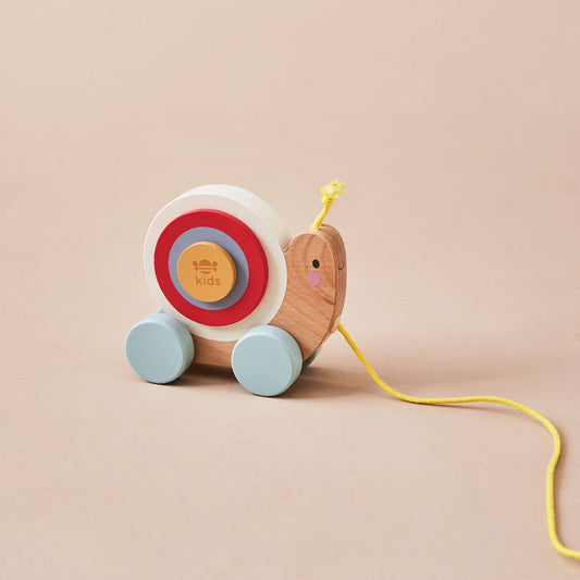 Wooden toy snail with colourful wheels on a beige background