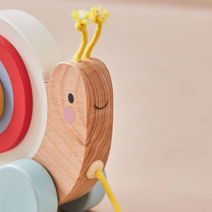 Wooden toy with a face and colourful wheels on a plain background