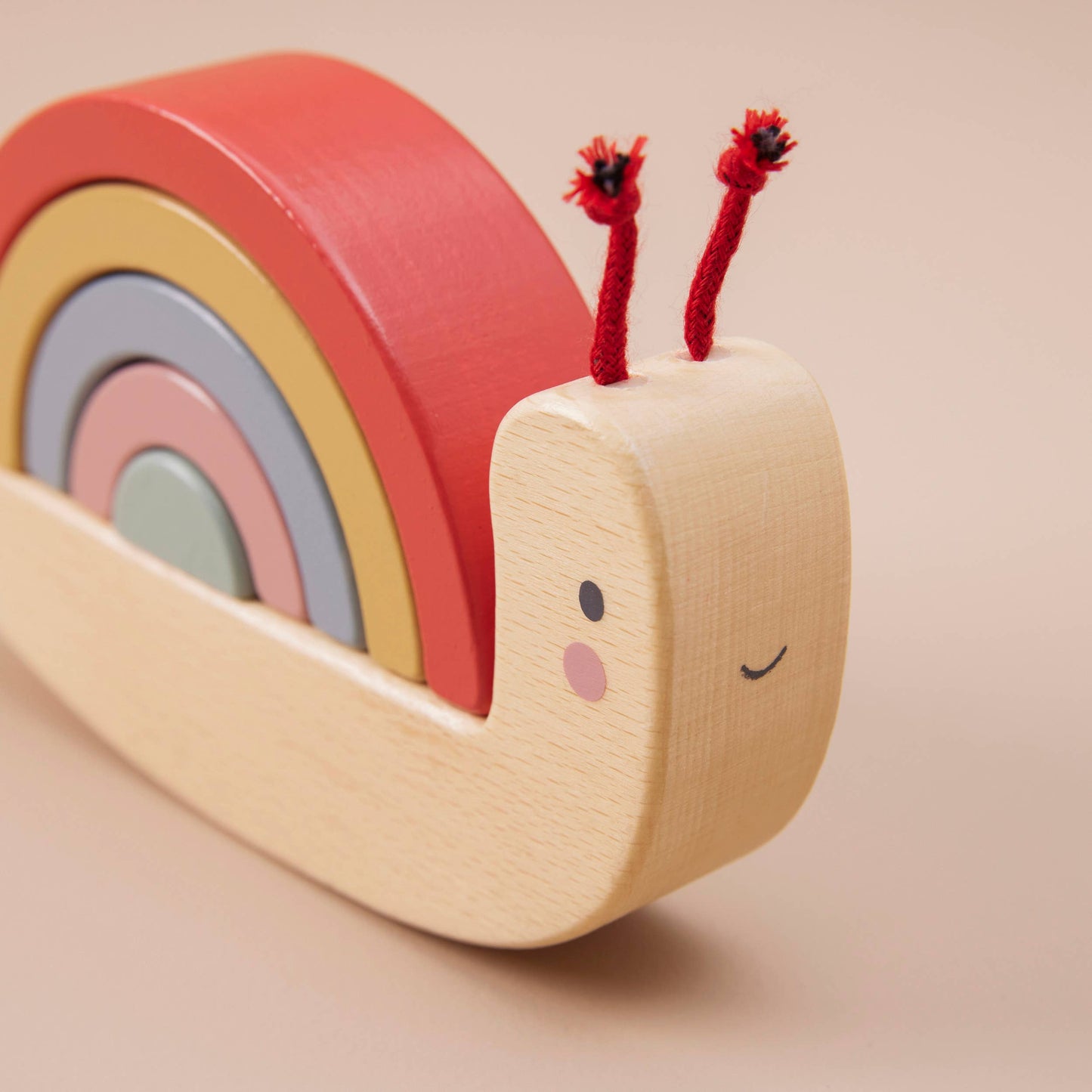 Wooden toy snail with colorful shell on a beige background