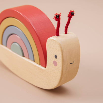 Wooden toy snail with colorful shell on a beige background