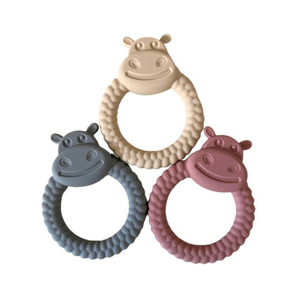 Three hippo-shaped teething rings in beige, gray, and pink on a white background