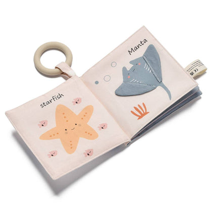 Children's soft book with marine animal illustrations and a ring for tummy time on a white background