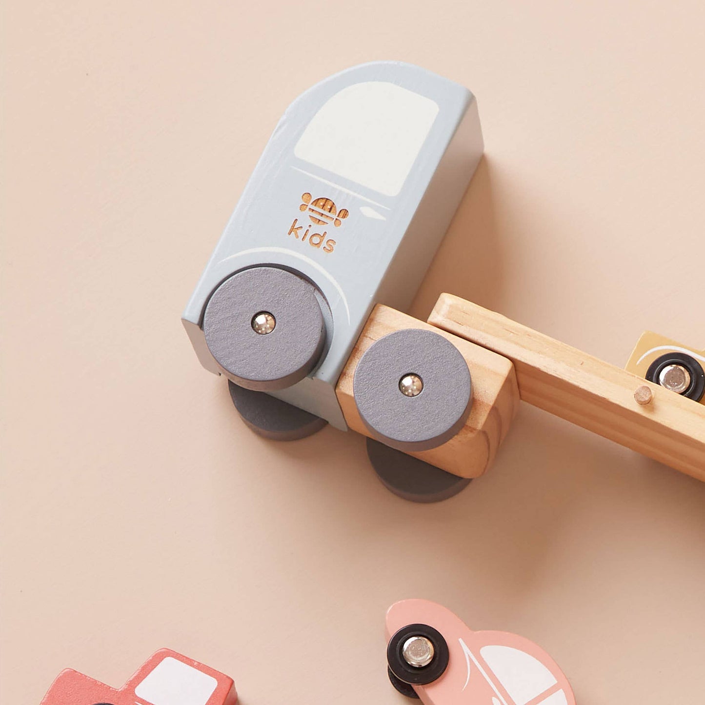 Wooden toy train with a gray engine and wooden carriages on a beige background