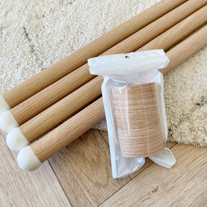 Wood effect chair legs with a clear plastic bag containing additional wood effect chair leg wrap on a textured surface.