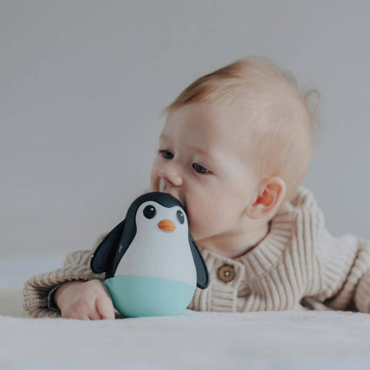 Baby holding a penguin toy with a plain background
