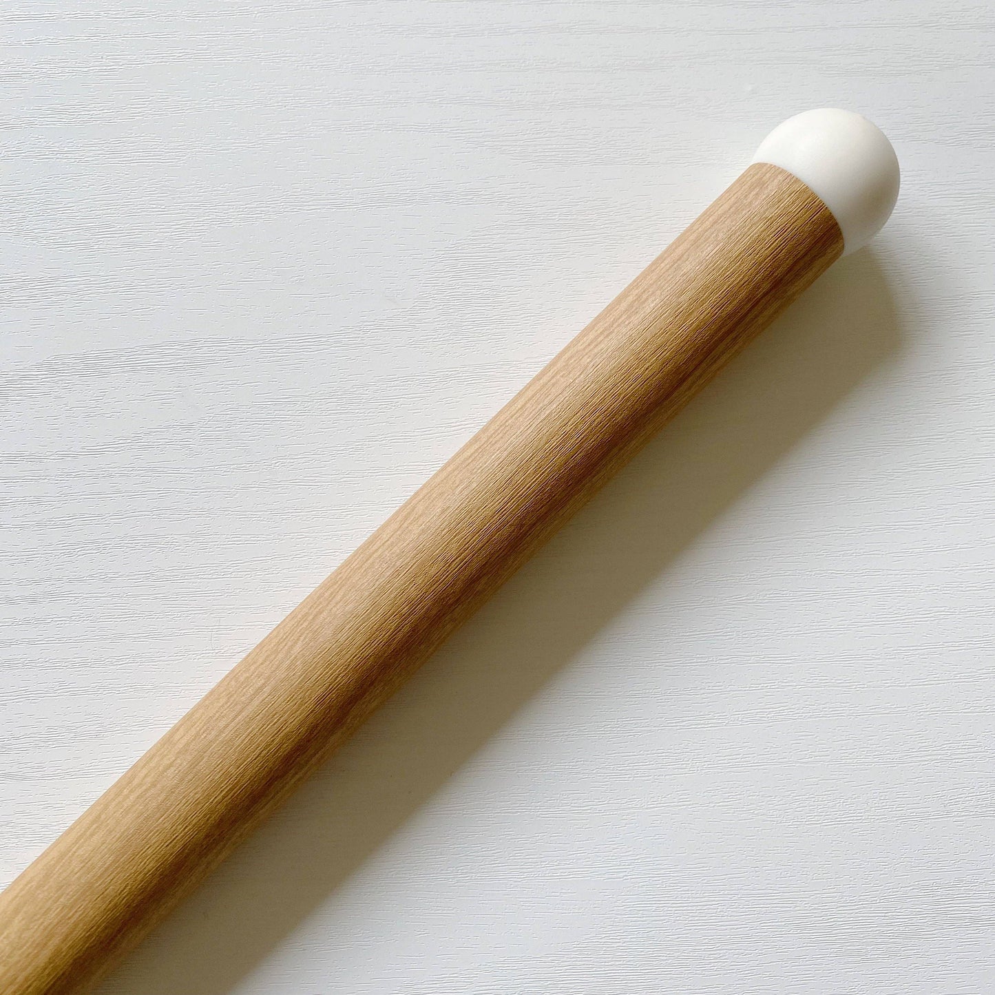 Wood effect chair leg cover with a white end on a light grey background